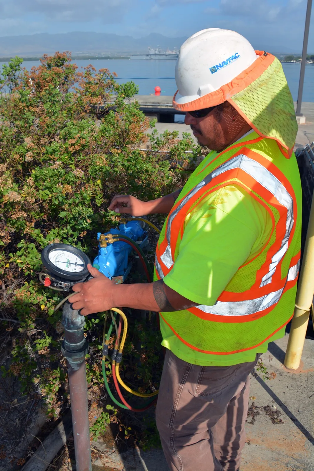 A technician connects a test kit to an above-ground backflow prevention assembly